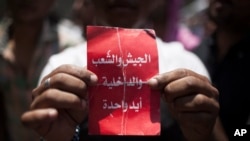 An Egyptian protester holds a card that says "army, people and police - one hand" during an spontaneous demonstration against Egypt's President Morsi in Tahrir Square in Cairo, June 29, 2013. 