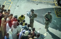 Dua tentara AS melakukan pengamanan sementara warga Afghanistan yang berusaha meninggalkan negaranya memenuhi bandara internasional Hamid Karzai di Kabul (16/8).