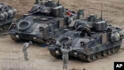 A U.S. Army soldier gestures to a fellow solider as they participate in annual military drills in Yeoncheon, South Korea, near the border with North Korea, April 11, 2013. 