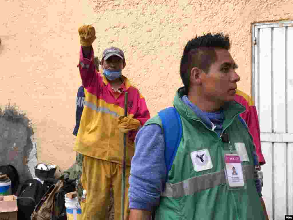 Rescue worker (rear, dressed in yellow) holds up his arm to request silence as they search for earthquake survivors in Mexico City, Mexico, Sept 21, 2017. (Photo: C. Mendoza / VOA)