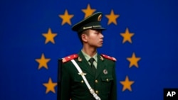FILE - A Chinese policeman stands in front of the European Union flag outside the office of the European Union delegation to China in Beijing, Oct. 28, 2011. The chamber said the EU is unlikely to lift trade barriers this year because of fears Chinese exports are causing job losses.