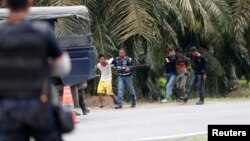 Malaysian police detain two men March 6, 2013, when they were coming out from Tanjung Labian, a village adjacent to Kampung Tanduo, a village adjacent to Kampung Tanduo, where Malaysian troops stormed the camp of an armed Filipino group on Tuesday. 