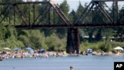 People gather at the Sandy River Delta, in Ore., to cool off during the start of what should be a record-setting heat wave on June 25, 2021.