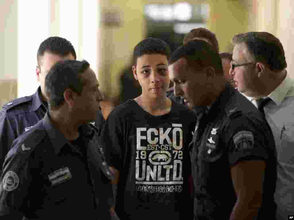 Tariq Abu Khdeir, 15, seorang warga negara AS yang disebut kerabatnya dipukuli dan ditahan polisi Israel dalam bentrokan yang dipicu pembunuhan sepupunya, dikawal oleh para penjaga penjara Israel saat hadir di sebuah pengadilan Yerusalem (6/7). (AP/Oded Balilty)