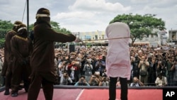 Shariah law official whips one of two men convicted of gay sex during a public caning outside a mosque in Banda Aceh, Aceh province, Indonesia, May 23, 2017. 
