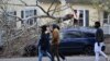 Un grupo de personas caminan frente a un auto sobre el que se derribó un árbol durante una tormenta en Issaquah, estado de Washington, el 20 de noviembre de 2024.