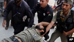 Pakistani security officials rush a colleague to a local hospital in Peshawar after the Taliban launched a brazen assault on a military base, Sept. 18, 2015.