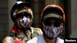 People wear protective masks while riding on a street in Hanoi, Vietnam, May 21, 2018. 