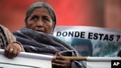 FILE - A relative of one of the 43 missing students from the Isidro Burgos rural teachers college stands on a stage with other missing student relatives during a protest in Mexico City, Dec. 6, 2014. 