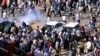 Demonstrators run from teargas lobbed to disperse them as they march along the street during anti-government protests in Khartoum, Sudan, Dec. 25, 2018. 