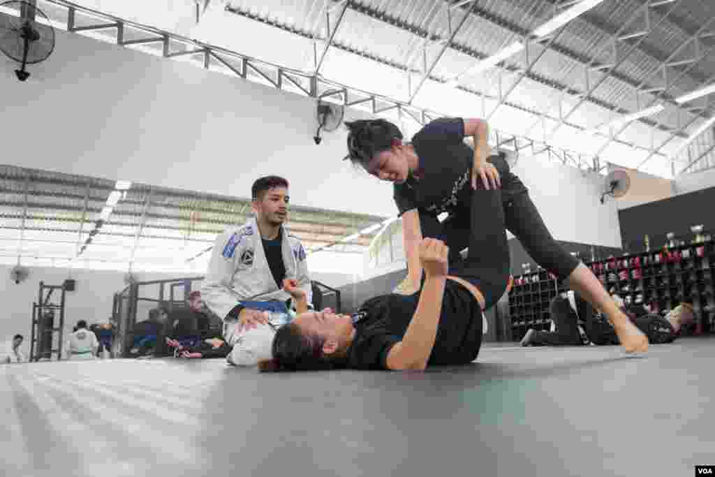 លោក ខូវ វិវត្តថានា (ខោអាវស) ជាគ្រូបង្វឹកមួយរូបក្នុងចំណោមគ្រូពីររូបរបស់ BJJ Cambodia បង្ហាត់ហ្វឹកហាត់កីឡា Jiu Jitsu ដល់សិស្សបរទេសរបស់ខ្លួនក្នុងក្លឹបកីឡាមួយ នៅរាជាធានីភ្នំពេញ កាលពីថ្ងៃទី២០ ខែកុម្ភៈ ឆ្នាំ២០១៦។ (នៅ វណ្ណារិន/VOA)