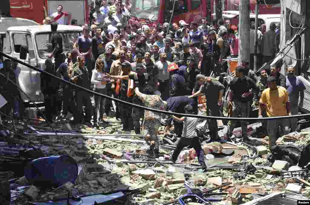 People gather around wreckage after a car bomb at the Wadi al-Dahab area of Homs in this picture released by Syria's national news agency SANA. The car bomb killed seven people and more than 55 were wounded, state media said.