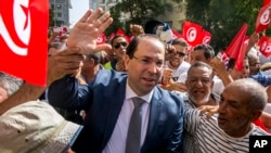 FILE - Tunisian Prime Minister Youssef Chahed, center, arrives to submit his candidacy for the upcoming early presidential elections in Tunis, Tunisia, Aug. 9, 2019.