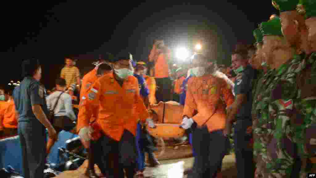 Indonesian members of search-and-rescue team carry a victim of AirAsia Flight 8501 that crashed in the Java Sea, in Kumai, Dec. 31, 2014.