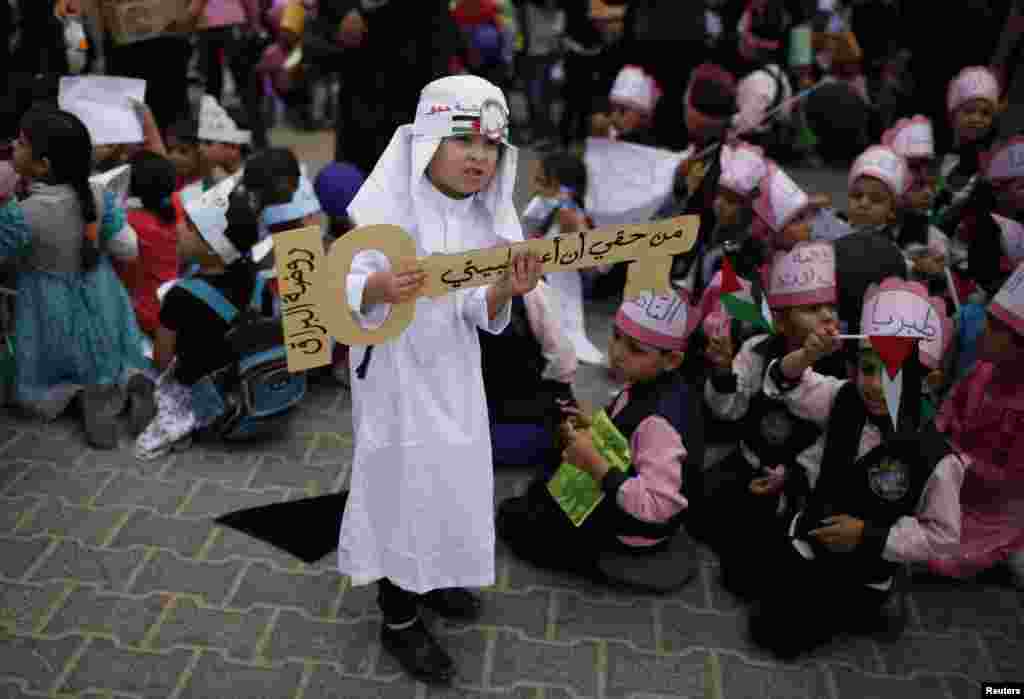 Seorang anak laki-laki Palestina membawa simbol kunci yang bertuliskan "Saya berhak untuk kembali ke rumah saya" saat unjuk rasa di Khan Younis, Jalur Gaza.