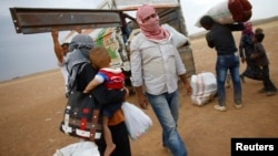 Kurdish Syrian refugees load their belongings on a truck on the Turkish-Syrian border near the southeastern town of Suruc in Sanliurfa province, Sept. 24, 2014.
