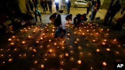 Varias personas encienden velas durante una vigilia frente a la sede de los Carabineros en honor de tres policías asesinados en el sur de Chile, el sábado 27 de abril de 2024, en Santiago. 