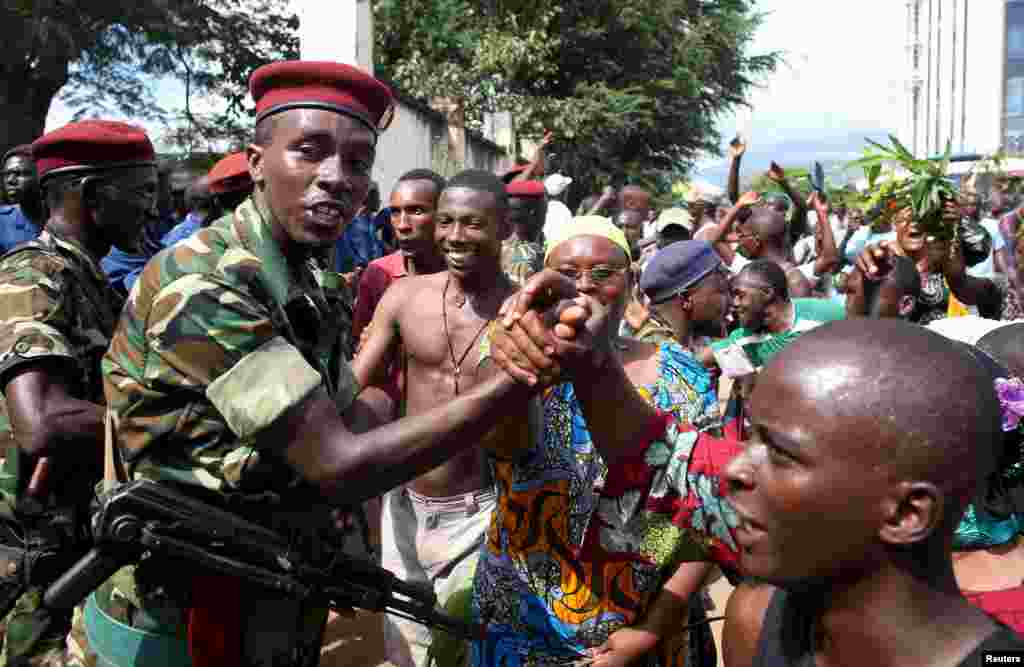 People greet soldiers as they celebrate in Bujumbura, May 13, 2015. Crowds poured onto the streets of Burundi's capital to celebrate after a general said he was dismissing President Pierre Nkurunziza for violating the constitution by seeking a third term in office, a Reuters witness said.