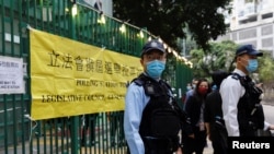 Petugas polisi tampak berjaga di luar tempat pemungutan suara di Hong Kong pada pemilu legislatif yang digelara pada 19 Desember 2021. (Foto: Reuters/Tyrone Siu)
