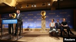 Hollywood Foreign Press Association President Theo Kingma speaks at the podium as (L-R) actors Zoe Saldana, Aziz Ansari and Olivia Wilde sit on stage at the announcement of nominations for the 71st annual Golden Globe Awards in Beverly Hills, California, 