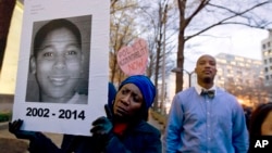 FILE - Tomiko Shine holds up a picture of Tamir Rice, the 12-year-old boy fatally shot on Nov. 22 , 2014 by a police officer, in Cleveland, Ohio, Dec. 1, 2014.