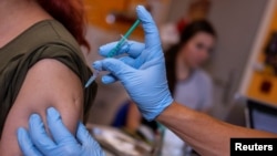 A doctor vaccinates a woman with a COVID-19 vaccine, in his office in Berlin, Germany, Nov. 2, 2021.