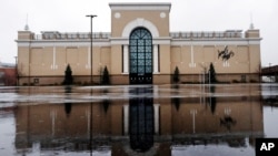 FILE - Rain drops fall on a puddle in an empty parking lot outside a Lord & Taylor store, closed due to the coronavirus outbreak, in Salem, New Hampshire, April 3, 2020. 