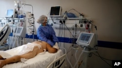 A health care worker tends to a COVID-19 patient at the Dr. Norberto Raul Piacentini hospital, in Lomas de Zamora, Argentina, April 23, 2021, amid the coronavirus pandemic.