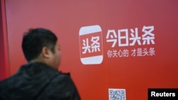一名男子走過北京街頭張貼的新聞類民營企業字節跳動公司(Bytedance}的新聞平台今日頭條的廣告。 （2017年10月26日）