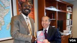 Rafael Marques à esquerda entregando o seu livro Diamantes de Sangue a Daniel Yamamoto do departamento de Estado americano