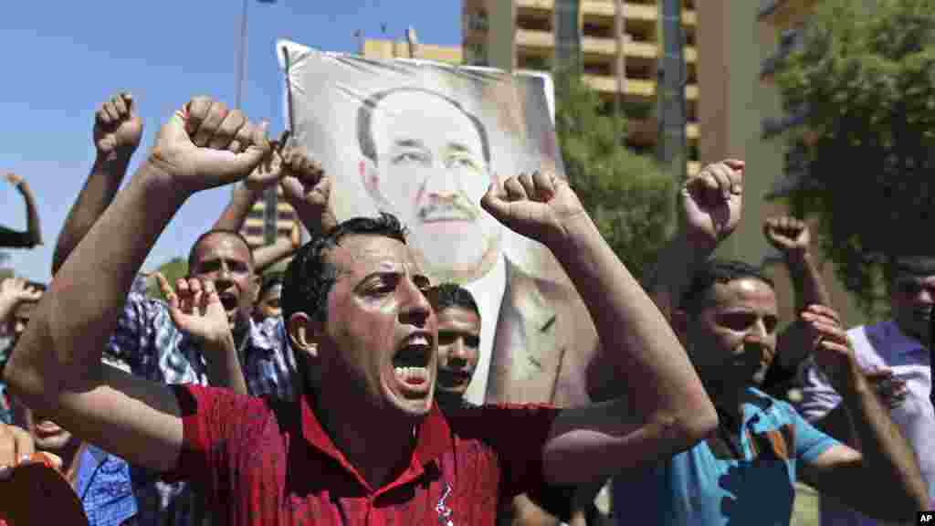 Iraqis chant pro-government slogans and display placards bearing a picture of embattled Prime Minister Nouri al-Maliki during a demonstration in Baghdad, Iraq, Aug. 11, 2014.