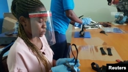 Des travailleurs tanzaniens confectionnent des écrans faciaux anti COVID-19,à partir de plastiques recyclés, lors de l'atelier Zaidi Recyclers , à Dar es Salaam, en Tanzanie, le 27 mai 2020. (Photo REUTERS / Stringer.)