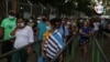 Trabajadores salen de una empresa privada en Managua, unos con máscaras, otros sin ellas. Foto VOA.