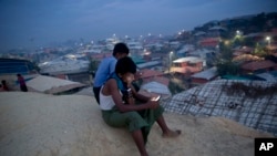 Rohingya Muslims use their cellphones as they sit on a hillock overlooking Balukhali refugee camp, in Bangladesh, Nov. 14, 2018. 