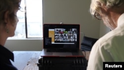 FILE - University of California, Berkeley Professors Lisa Wymore (L) and Greg Niemeyer look at the Zoom screen showing students in their online Collaborative Innovation course in Berkeley, California, March 12, 2020.
