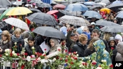People place flowers near the entrance of a courthouse where the trial of Anders Behring Breivik is conducted, as thousands turn up in poor weather to sing a popular children's song in Oslo April 26, 2012.