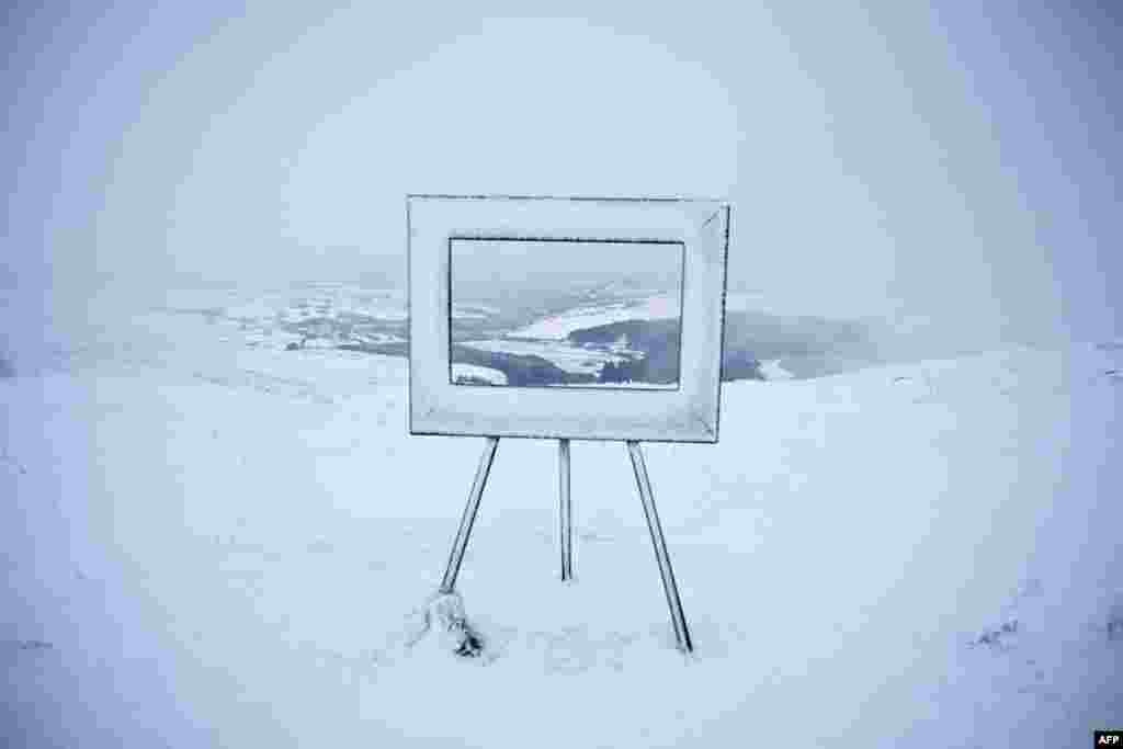 Fog and snow surround an art installation, giving a pictured-framed view over the valley beneath, at the summit of Holme Moss in the Peak District, in northern England, after snow and rain continued to fall across parts of the United Kingdom. 