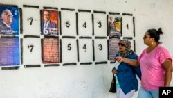 Women walk past a wall of campaign posters in Tunis, Tunisia, Sept. 2, 2019.