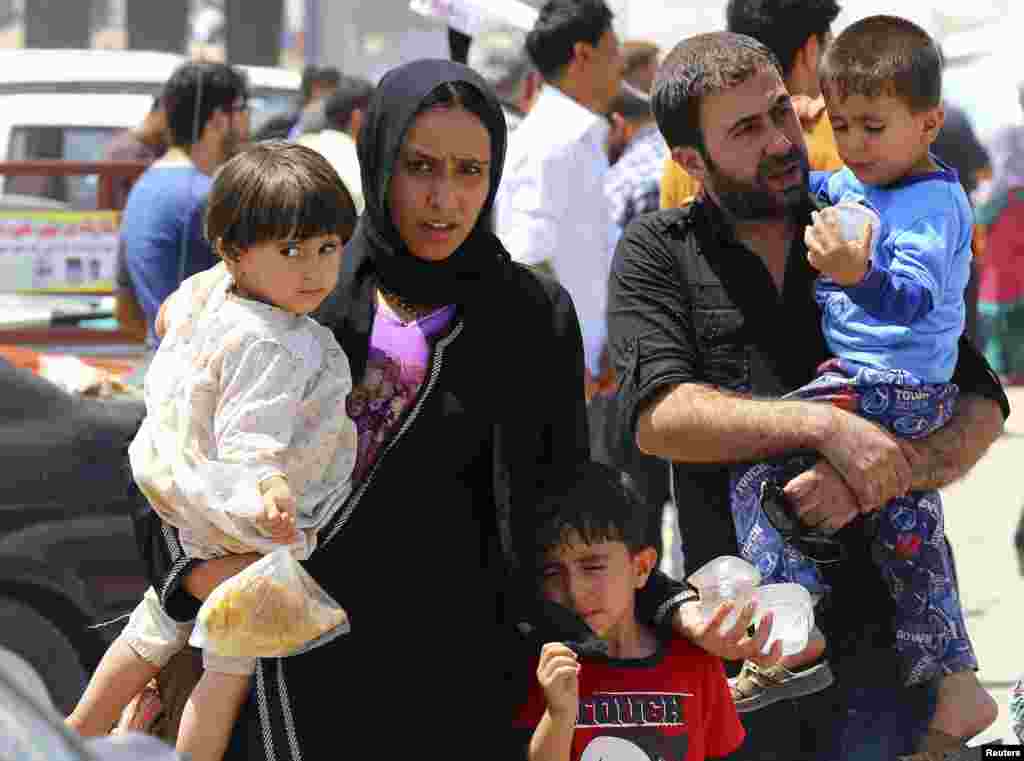 A family fleeing the violence in the Iraqi city of Mosul waits at a checkpoint in outskirts of Arbil in Kurdistan region. Radical Sunni Muslim insurgents seized control of most of Mosul, the country's second largest city.
