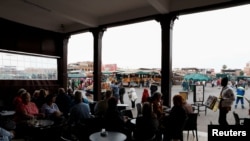 Des touristes sont assis dans un café de la place Jamaa Lafna à Marrakech, Maroc, le 15 mars 2020. REUTERS / Youssef Boudlal