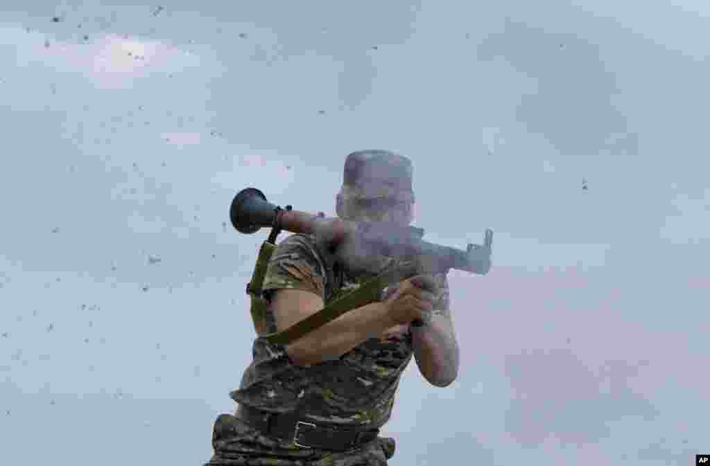 A pro-Russian rebel fires a rocket propelled grenade on the rooftop of an apartment building during clashes with Ukrainian troops on the outskirts of Luhansk, Ukraine.