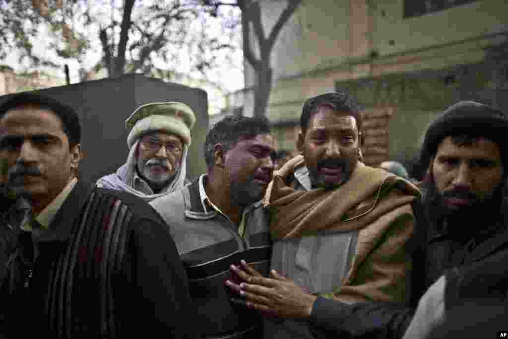 Uncles of a student who was killed in a suicide bombing comfort each other as his body is loaded to an ambulance for burial, at a hospital in Rawalpindi, Pakistan, Jan. 20, 2014.