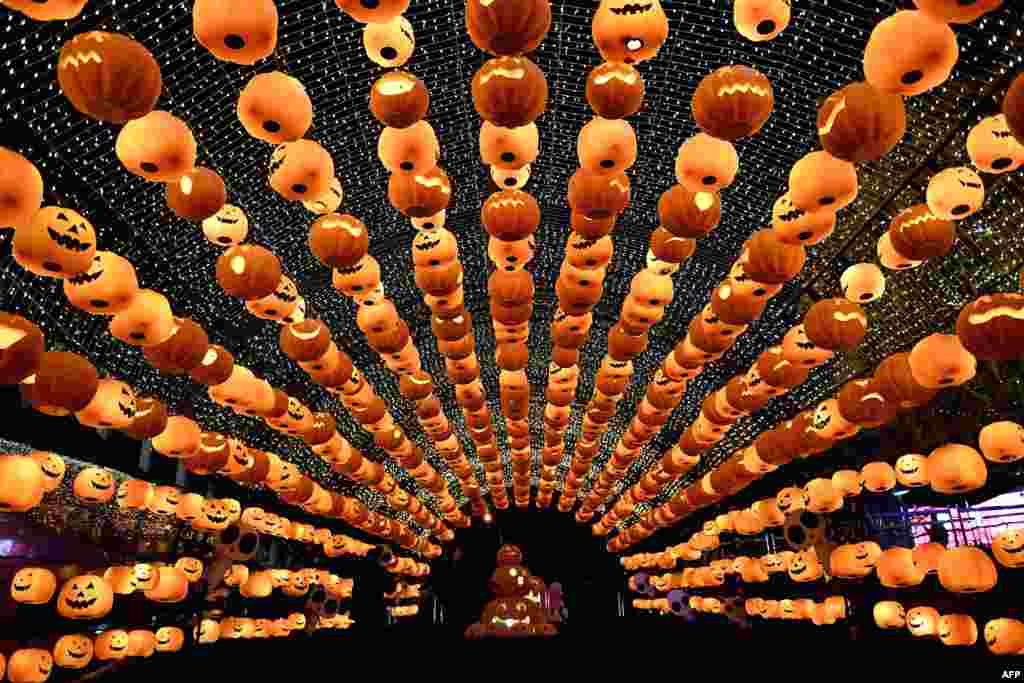 Para pengunjung melewati lentera-lentera yang dibuat dari labu untuk memperingati 'Halloween' di pusat perbelanjaan di Shenyang, Liaoning, China.