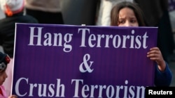 Seorang anak pendukung partai politik di Pakistan memegang papan berisi kutukan atas terorisme dalam demonstrasi di Lahore yang mengecam serangan Taliban di Peshawar (21/12). (Reuters/Mohsin Raza)