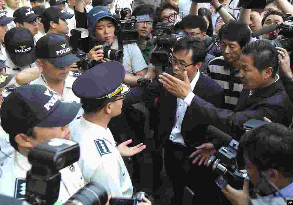 Para anggota keluarga penumpang kapal kapal feri Sewol yang tenggelam meminta pada polisi untuk bertemu awak kapal usai sidang pra-peradilan untuk mereka di Pengadilan Distrik Gwangju, Gwangju, Korea Selatan (10/6). (AP/Ahn Young-joon)