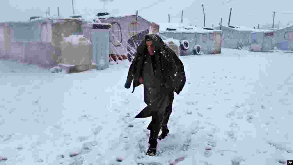 A Syrian man walks in the snow at a refugee camp in Deir Zannoun village, in the Bekaa valley, east Lebanon, Jan. 7, 2015.