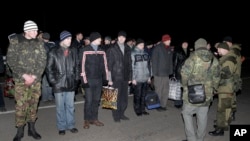 Warga Rusia (membelakangi kamera, sebelah kanan) dan militer Ukraina bersiap untuk pertukaran tahanan perang di luar wilayah Donetsk, Ukraina Timur (26/12).