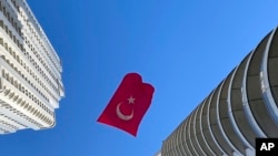 A Turkish flag suspended between two skyscrapers flutters in the wind, in Istanbul, April 23, 2020, to mark centennial celebrations for the founding of Turkey's parliament.