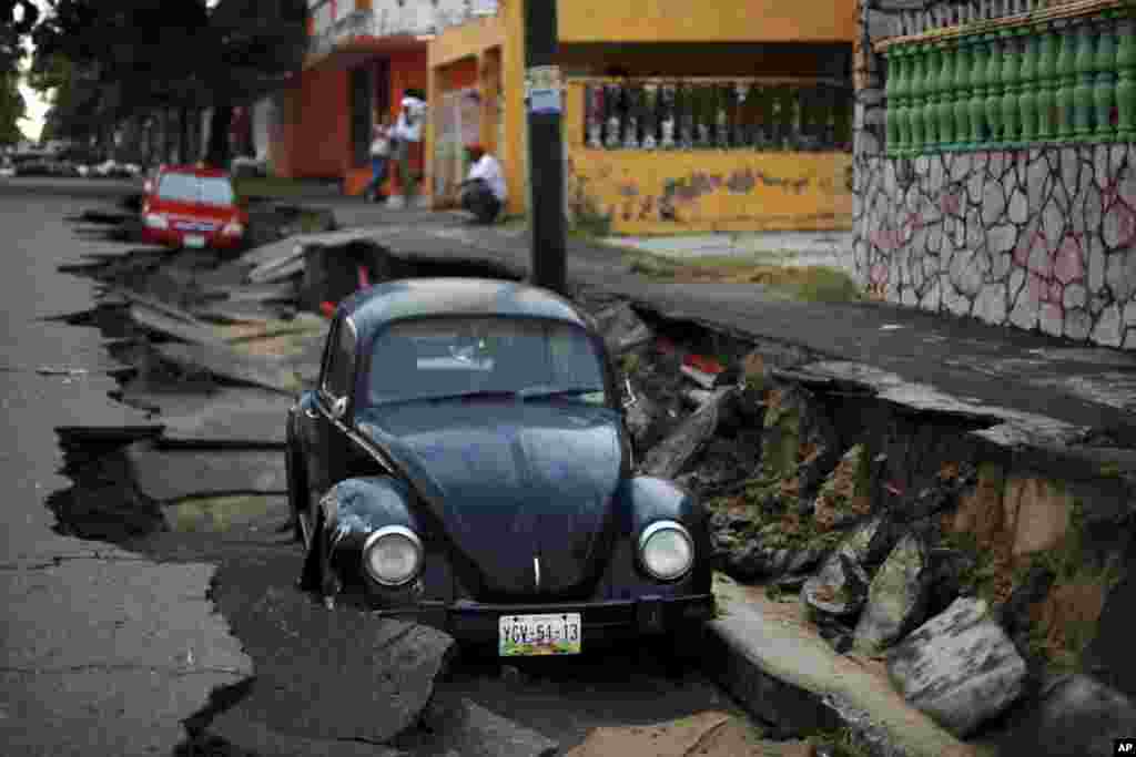 Cars sit on a street that collapsed after heavy rain in the Gulf port city of Veracruz, Mexico, Sept. 2, 2014.