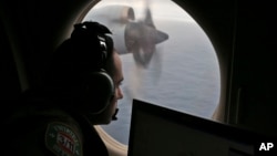 FILE - In this March 22, 2014, photo, a flight officer aboard a Royal Australian Air Force plane, searches for signs of missing Malaysia Airlines Flight MH370 in the southern Indian Ocean off Australia.